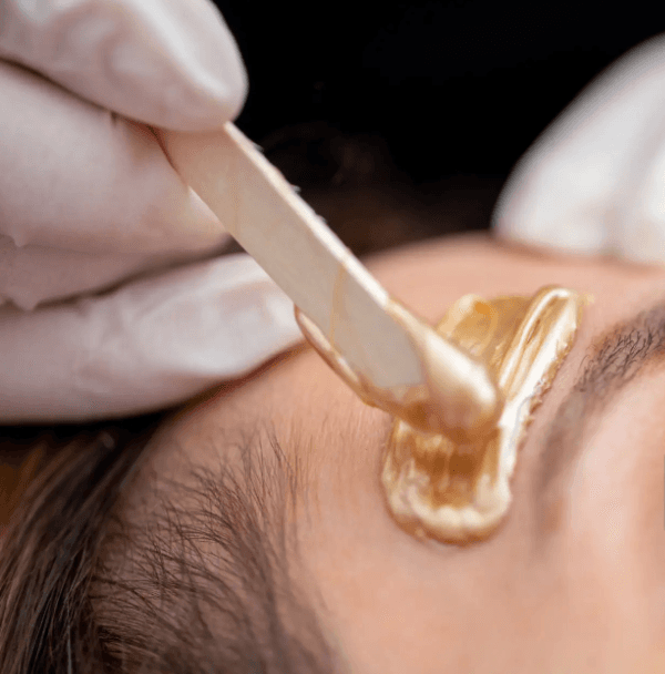 Close-up of warm wax being applied to a brow during a facial waxing treatment